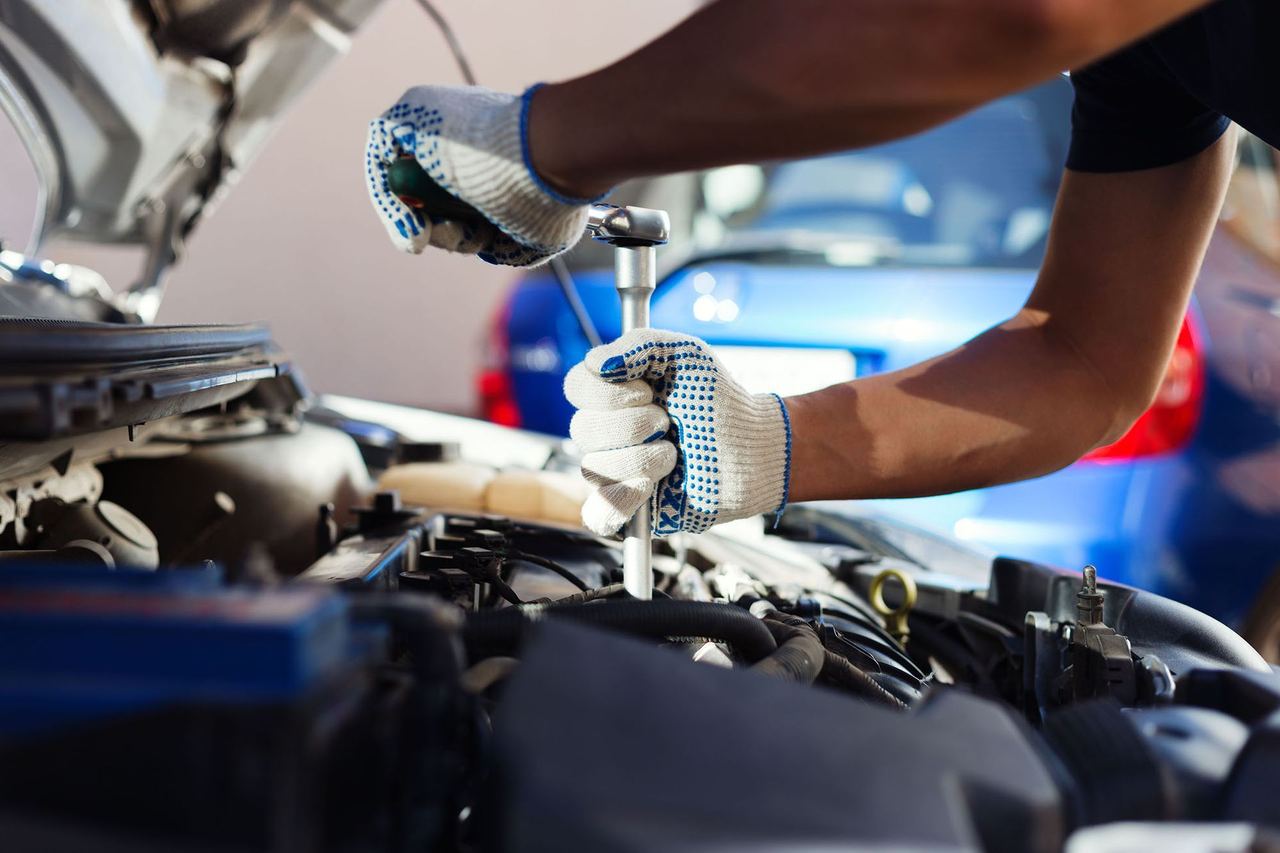 Mechanic using a ratchet wrench on a car engine